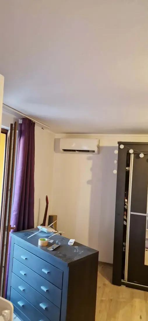 Aparat de aer condiționat interior alb, montat pe perete într-un dormitor