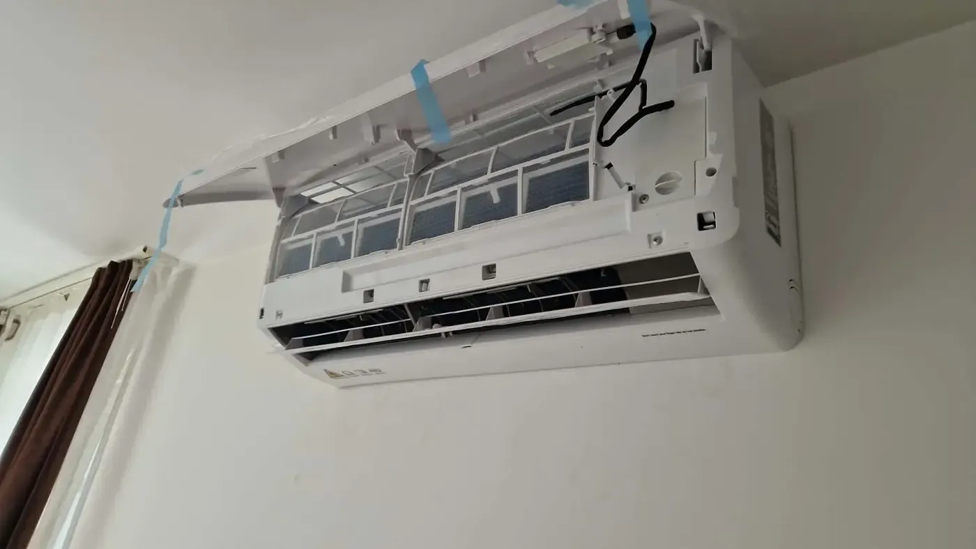 Aparat de aer condiționat interior cu capacul frontal ridicat și filtrele la vedere, în timpul montajului