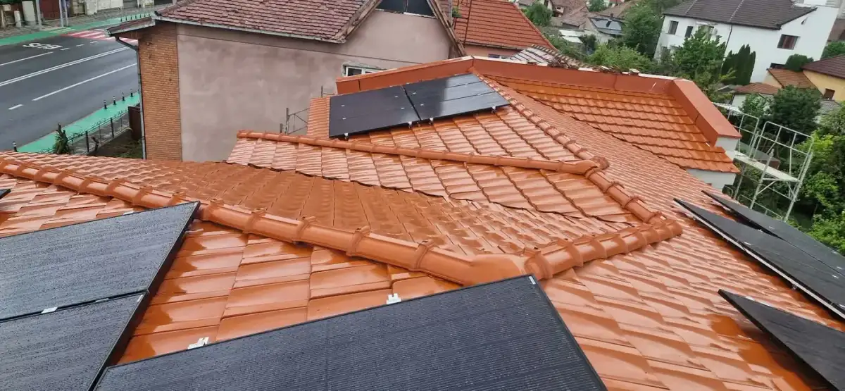 Acoperiș de țiglă ceramică portocalie văzut de sus, cu panouri fotovoltaice negre așezate pe el